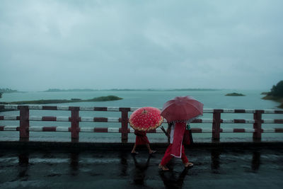 Mother and daughter walking across bridge with umbrella 