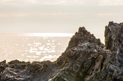 Rock formation on beach against sky during sunset