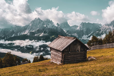 Built structure on field by mountain against sky