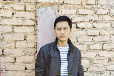 Portrait of man standing against brick wall