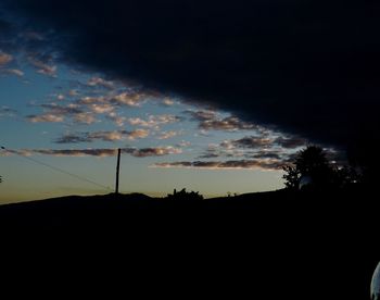 Silhouette of electricity pylon against dramatic sky