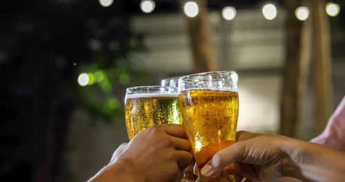 Cropped hands of friends toasting beer glasses