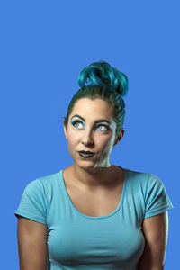 Portrait of young woman against blue background