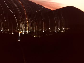 Panoramic view of illuminated silhouette mountain against sky at night