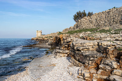 Scenic view of sea and ancient tower against clear sky