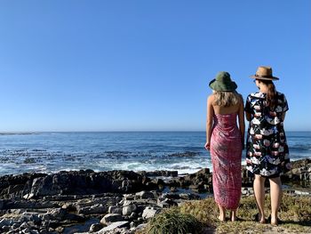 Rear view of woman standing at beach against clear sky