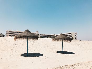 Traditional windmill on beach against clear sky