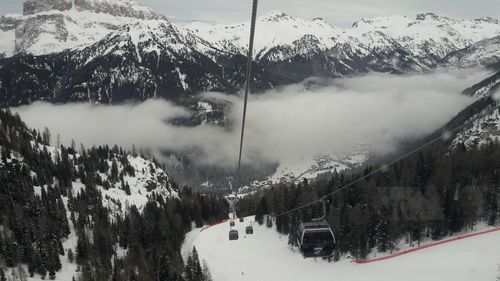 Ski lift over snowcapped mountains against sky