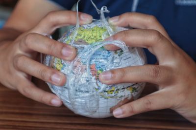 Midsection of woman holding globe in plastic on table