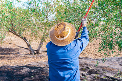 Rear view of man wearing hat standing on field