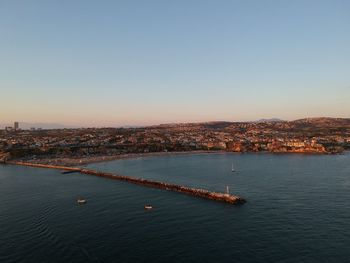 High angle view of cityscape by sea against clear sky
