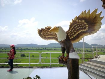 Full length of man standing on railing against sky