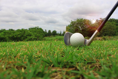 Close-up of golf ball on field against sky