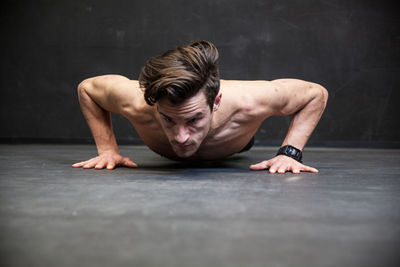 Shirtless man doing push ups in gym