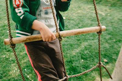 Low section of man standing on swing at playground