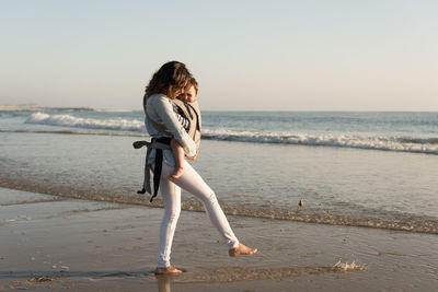 Mother carrying son while walking at beach