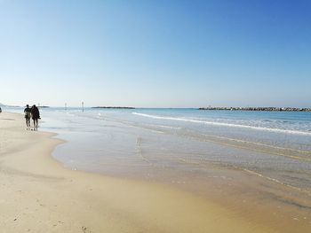 Scenic view of beach against clear blue sky