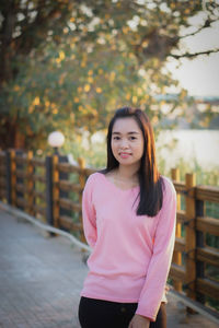 Portrait of young woman standing against trees