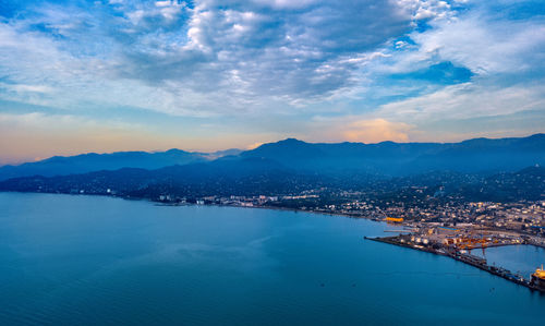 High angle view of illuminated city by sea against sky