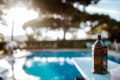 Close-up of bottle by swimming pool against sky