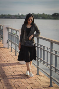 Portrait of young woman standing against railing