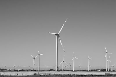 Wind turbines on field against clear sky