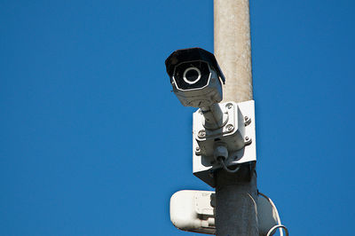 Low angle view of electric lamp against blue sky