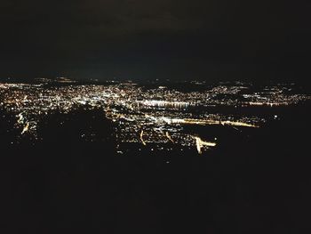 Illuminated cityscape against sky at night