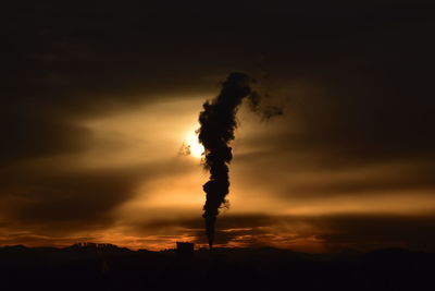 Silhouette of smoke stack against sky during sunset