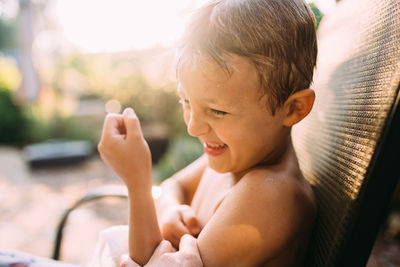 Shirtless boy being tickled while sitting on chair