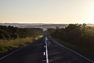 Empty road amidst landscape against clear sky