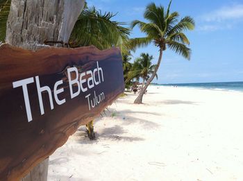 Information sign on beach against sky