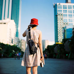 Rear view of woman standing on street against sky in city