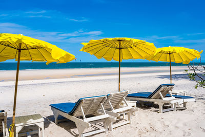 Lounge chairs and parasols on beach against sky