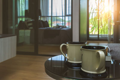 Couple white coffee cups on black table in comfortable room with sunrise lighting and copy space.