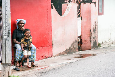 People on footpath by red wall