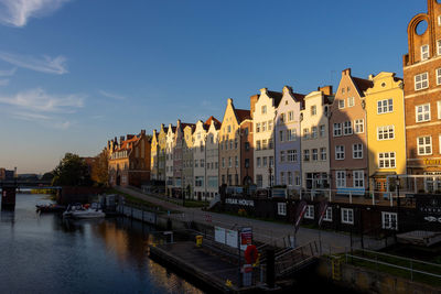 Buildings by river against sky in city