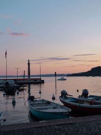 Boats moored on sea against sky during sunset