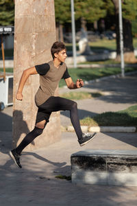 Full length side view of young man running on footpath