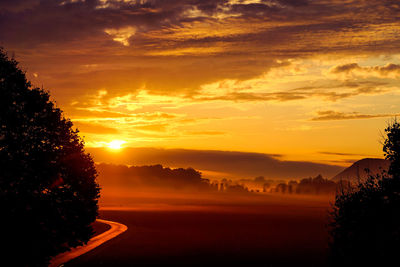 Scenic view of silhouette landscape against orange sky