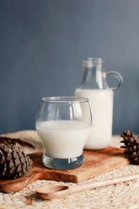 A bottle of milk and glass of milk on wooden cutting board