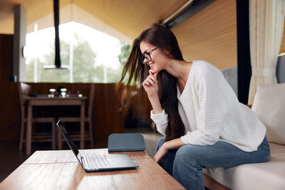 Young woman using mobile phone while sitting at home