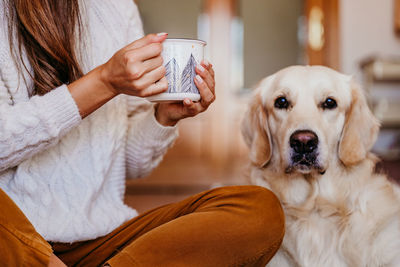 Midsection of woman with dog at home