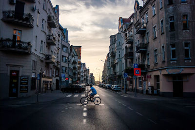 Side view of man riding bicycle on road in city