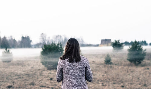 Rear view of woman standing on field against sky