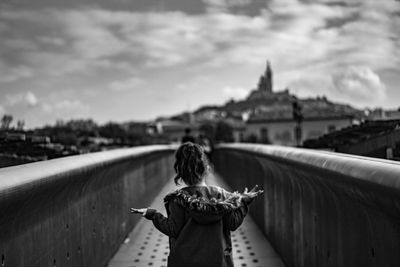 Rear view of woman looking at city buildings against sky