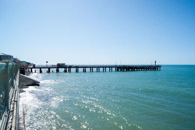 Pier over sea against clear blue sky