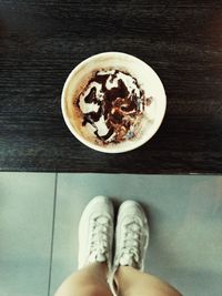 Low section of woman with coffee cup on floor