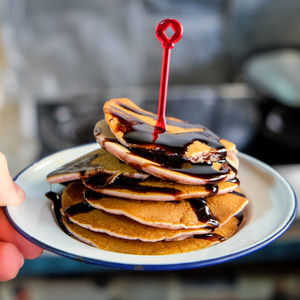 Cropped image of hand holding pancakes in plate