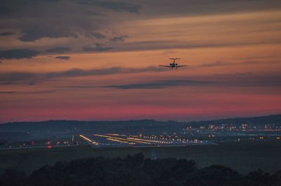 Aerial view of illuminated city against sky during sunset